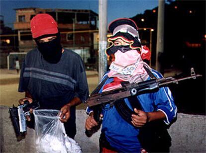 Dos menores enmascarados exhiben drogas y armas en una calle de Río de Janeiro.