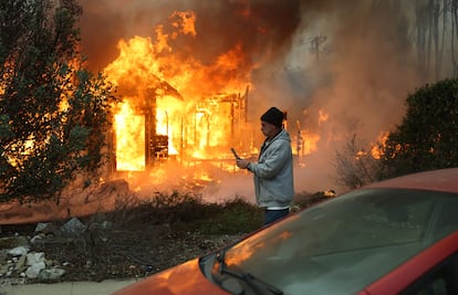 Una persona pasa junto a una casa en llamas durante el incendio Eaton en Altadena, California. 