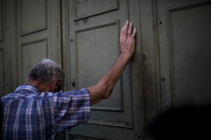 Um pensionista se apoia na porta principal do Banco Nacional da Grécia enquanto espera para retirar um máximo de 120 euros para a semana, em Atenas.