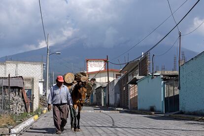 Las Fuerzas Armadas han dado a conocer que están preparadas para trasladar hasta 900 personas a los seis albergues operados por la Sedena. En la imagen, un hombre y su caballo caminan por una calle de la comunidad de San Pedro Benito Juárez, aledaña al volcán.