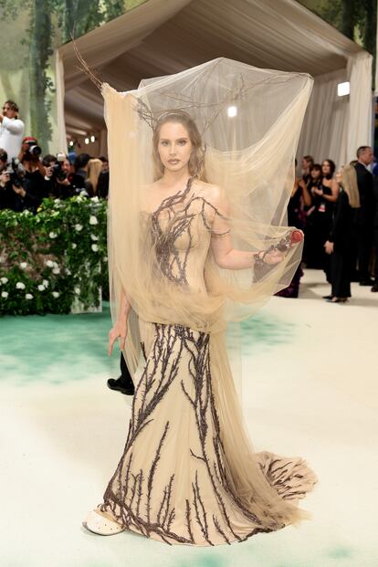 El 'look' de la cantante Lana del Rey para la Met Gala 2024 hacía referencia a una colección icónica de Alexander McQueen, exactamente a la del otoño/invierno de 2006. El estilismo, creado por el actual director creativo de la marca británica, Seán McGirr, era etéreo, oscuro y romántico: como lo describió 'Vogue', se trataba de un vestido encorsetado de seda, georgette doble y tul, todo bordado a mano con ramas de espino martilladas con cascabeles de bronce, inspiradas en la pátina y la forma de las esculturas del artista suizo Alberto Giacometti. El espectacular tocado utilizaba ramas naturales de espino y tul transparente.