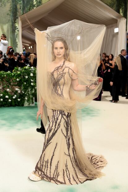 El 'look' de la cantante Lana del Rey para la Met Gala 2024 hacía referencia a una colección icónica de Alexander McQueen, exactamente a la del otoño/invierno de 2006. El estilismo, creado por el actual director creativo de la marca británica, Seán McGirr, era etéreo, oscuro y romántico: como lo describió 'Vogue', se trataba de un vestido encorsetado de seda, georgette doble y tul, todo bordado a mano con ramas de espino martilladas con cascabeles de bronce, inspiradas en la pátina y la forma de las esculturas del artista suizo Alberto Giacometti. El espectacular tocado utilizaba ramas naturales de espino y tul transparente.
