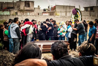 Familiares, amigos y vecinos de la víctima lloran y se abrazan al rededor del féretro.