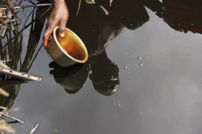 Un agricultor recoge una muestra de crudo en Ibeno (Nigeria) producto del vertido de ExxonMobil, en el Delta del Níger. Una prueba del desastre que representan para la agricultura de la zona.
