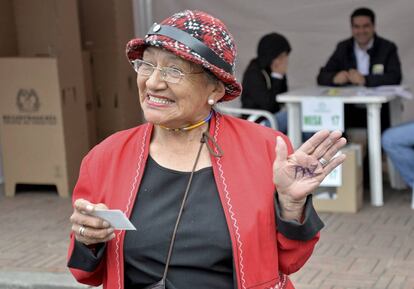 Una mujer, después de votar, muestra su mano. Ha escrito la palabra "Paz".