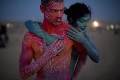 Una pareja con los cuerpos pintados pasea por el desierto al caer la noche.