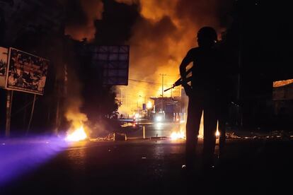 Un policía indonesio permanece en guardia junto a un edificio en llamas tras una multitudinaria manifestación celebrada en Jayapura (Papúa).