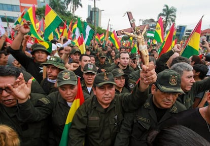 Un oficial de policía sostiene un crucifijo en una concentración junto a otros oficiales para celebrar la renuncia del presidente boliviano.