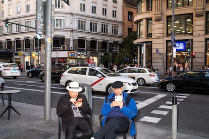 Dos turistas sentados en medio de la Gran Vía.