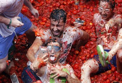 Un joven se hace un selfi junto a otros participantes sentados sobre tomates.