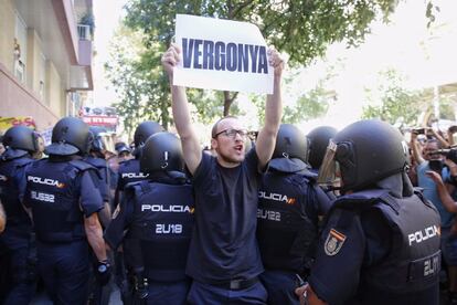 Un manifestante alza un cartel en el que se puede leer "Vergüenza" ante los antidisturbios.