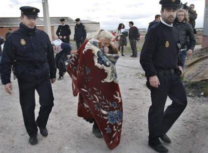 Dos agentes acompañan a la abuela de dos niños muertos en un incendio en Villaverde (Madrid).
