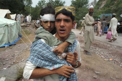 Un padre lleva a su hija en brazos a un hospital de campaña en Muzaffarabad.