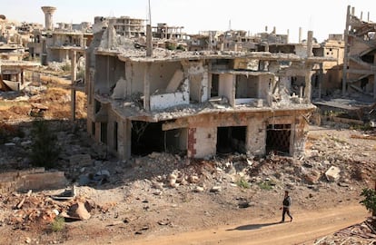 Un rebel camina davant de construccions destrossades a la part rebel de Deraa.