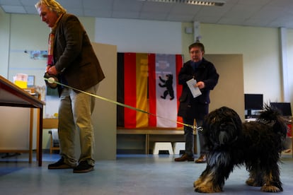 Una persona acompañado de su mascota vota en un centro de votaciones de Berlín, este domingo. 