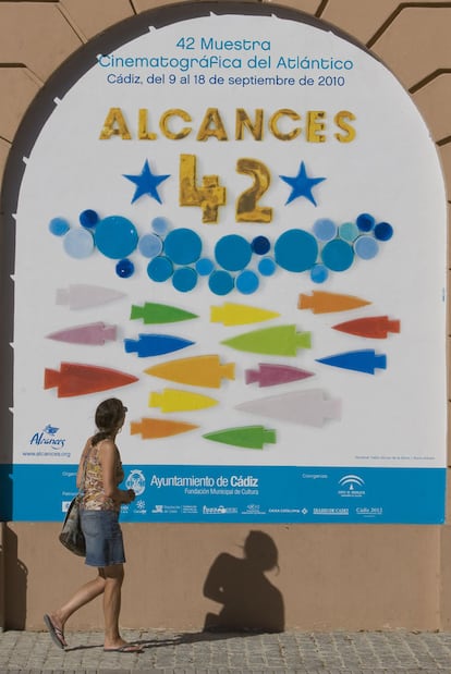 Una joven observa el cartel del festival cinematográfico Alcances en Cádiz.