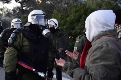 La policía antidisturbios se encara con un manifestante de un grupo que trata de bloquear la carretera próxima al lugar donde se construirá el centro de detención de migrantes, en la isla griega de Lesbos.