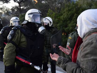 La policía antidisturbios se encara con un manifestante de un grupo que trata de bloquear la carretera próxima al lugar donde se construirá el centro de detención de migrantes, en la isla griega de Lesbos.