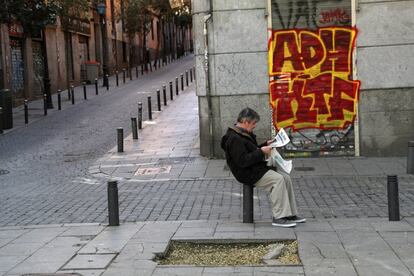 Un hombre lee un ejemplar del diario EL PAÍS en una calle de Madrid.