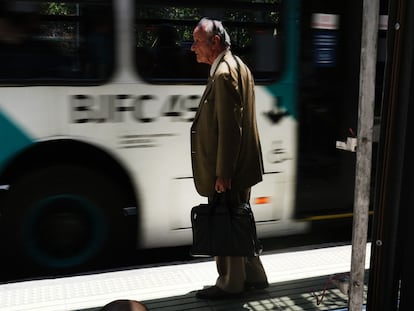 Un hombre espera por el transporte público al salir de trabajar, en Santiago.