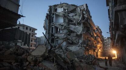 Un par de personas camina junto a un edificio bombardeado en Alepo.