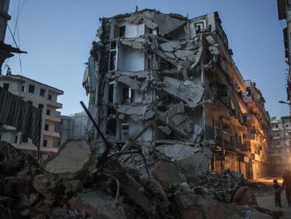 Un par de personas camina junto a un edificio bombardeado en Alepo.