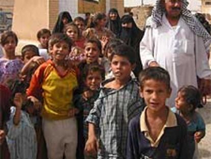 Un grupo de desplazados posa junto a un retrato de Sadam en Maqdadiya.