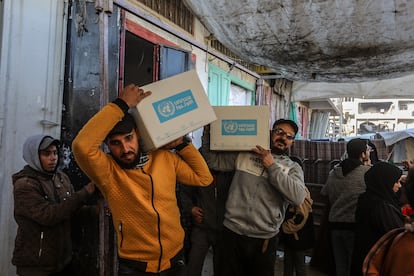 Dos personas cargan cajas de ayuda humanitaria distribuida por la UNRWA en Jan Yunis (sur de Gaza), el 21 de enero.