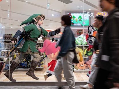 Passersby walk past a shop window in Tokyo displaying advertisements for the new 'Zelda' video game.