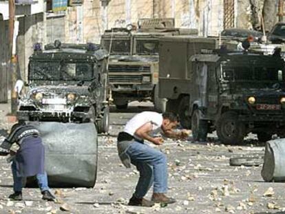 Dos jóvenes palestinos lanzan piedras contra vehículos blindados israelíes ayer en Ramala.