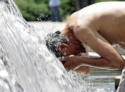 Un hombre se refresca en una fuente de la plaza de España.