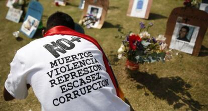 A man standing in front of the tombstones of people who died violently in Venezuela.