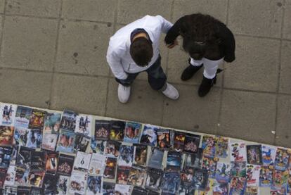 Dos peatones ojean unos discos en una calle de Sevilla.