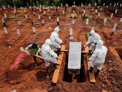Un grupo de personas con trajes aislantes entierran a una víctima de coronavirus en un cementerio de Yakarta, Indonesia, este martes.