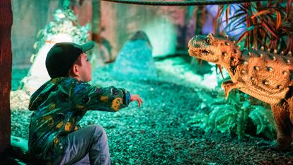 Un niño ruge a un ejemplar de la exposición 'Dinoworld' en Ifema.