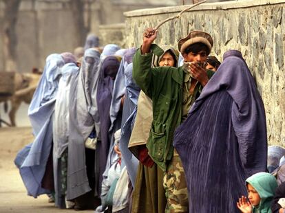 Un soldado afgano golpea a una mujer con una vara en una fila frente a la sede del Programa Mundial de Alimentos en Kabul, el 24 de diciembre de 2001, poco después de la caída de los talibanes.