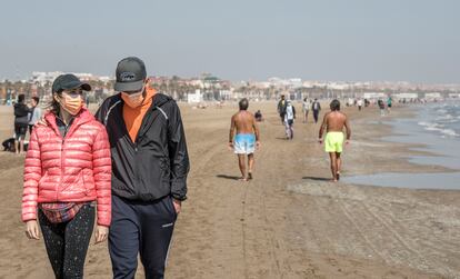 People walking down a beach in Valencia on March 31.  