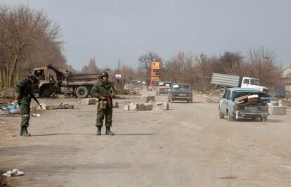 Militares prorrusos montan guardia a la salida de la caravana de coches que abandonan Mariupol, este jueves.