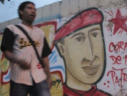 Un hombre camina por Caracas frente a la imagen de Chávez.
