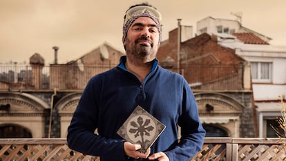 Joan Moliner sostiene en su casa una baldosa del año 1900 de la fábrica Escofet. Es un diseño de Enric Moyà. En la página siguiente, un catálogo de las piezas y la terraza-estudio de Moliner.
