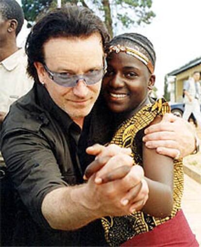 El cantante Bono baila en Kampala con una ni?a, hurfana a causa del sida.