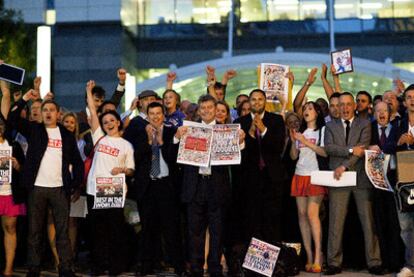 Miembros de la redacción de <i>News of The World</i> enseñan la portada del último número ante la sede de la empresa editora, en Londres.