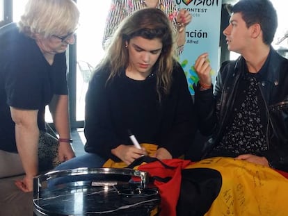 Amaia y Alfred firman en una bandera española con toro.