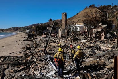 Firefighters search for hot spots in a house burned by the Palisades fire on January 12.