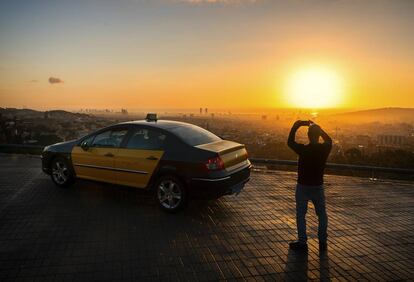 Barcelona. Un taxista de la capital catalana toma fotografías del perfil urbano desde lo alto del monte Tibidabo al amanecer.