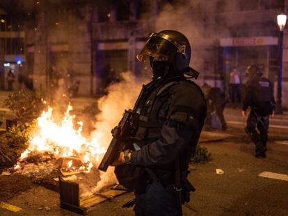 Un policía junto a una maceta incendiada por los manifestantes que protestaron el viernes por la noche en Barcelona contra el toque de queda.
