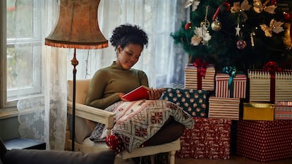 Una chica leyendo en casa junto al árbol de navidad.