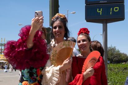 Tres mujeres vestidas de flamencas se fotografían junto a un termómetro que marca 41 grados centígrados en la avenida Flota de Indias, el martes.

