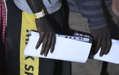 Dos migrantes llevan informes en sus manos antes del desembarco en la isla italiana de Lampedusa.