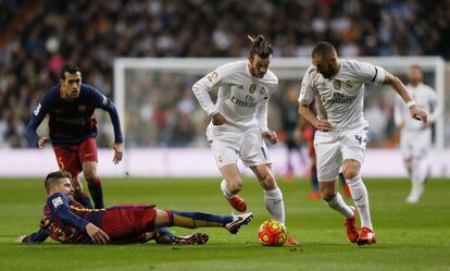 Gerard Piqué, arran de gespa, intenta robar una pilota a Gareth Bale i Benzema.